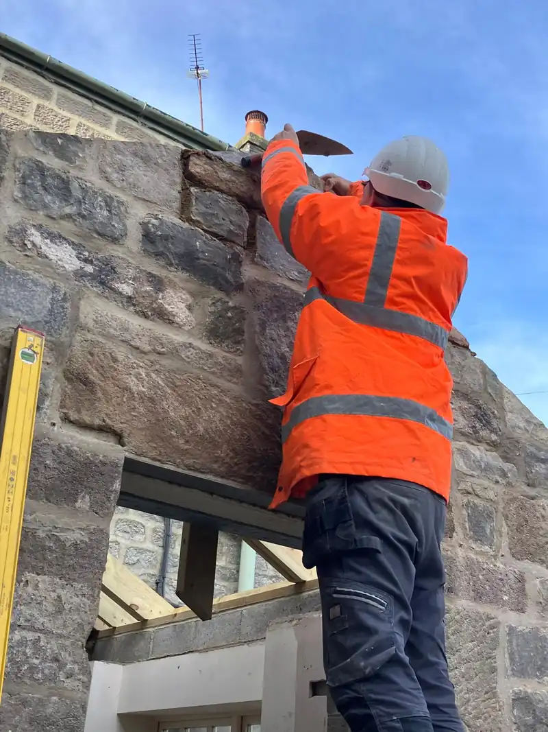 Barlow stonemason rebuilding a stone gable on scaffold
