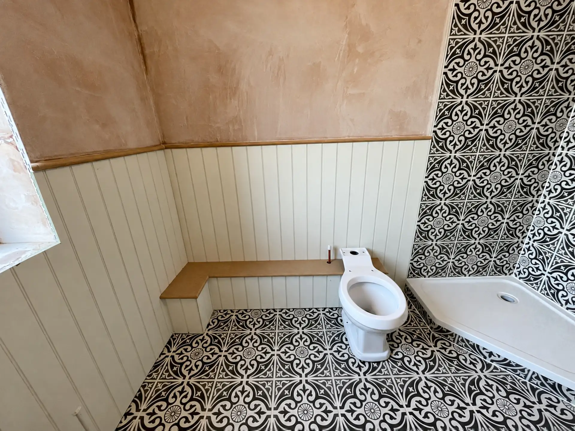 Bathroom with patterned floor and wall tiles and wood panelling