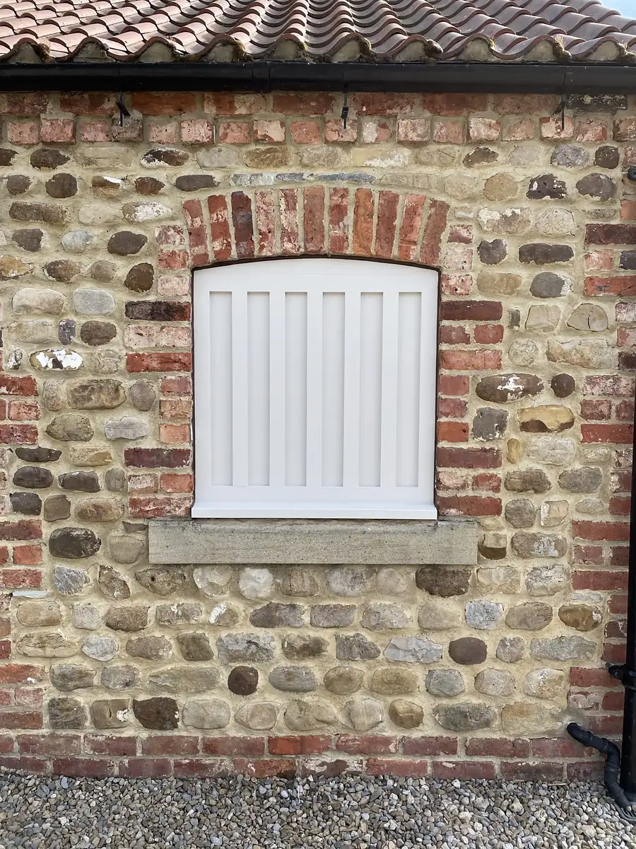 Brick and stone wall with a louvred shutter