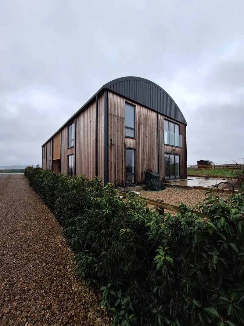 Finished timber clad Dutch barn house with a curved roof