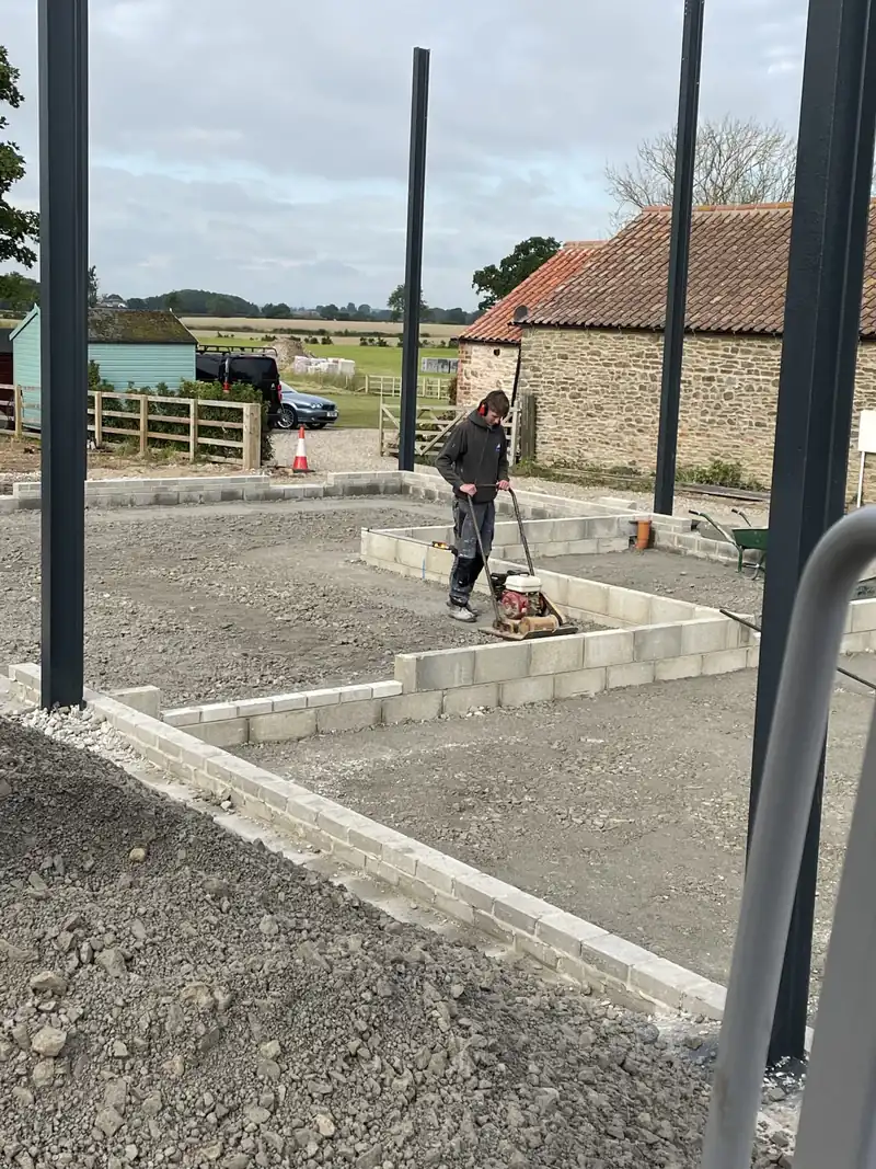 Foundation blockwork going in between the steel columns of a Dutch barn