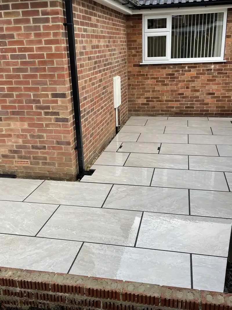 Grey porcelain patio beside a brick house