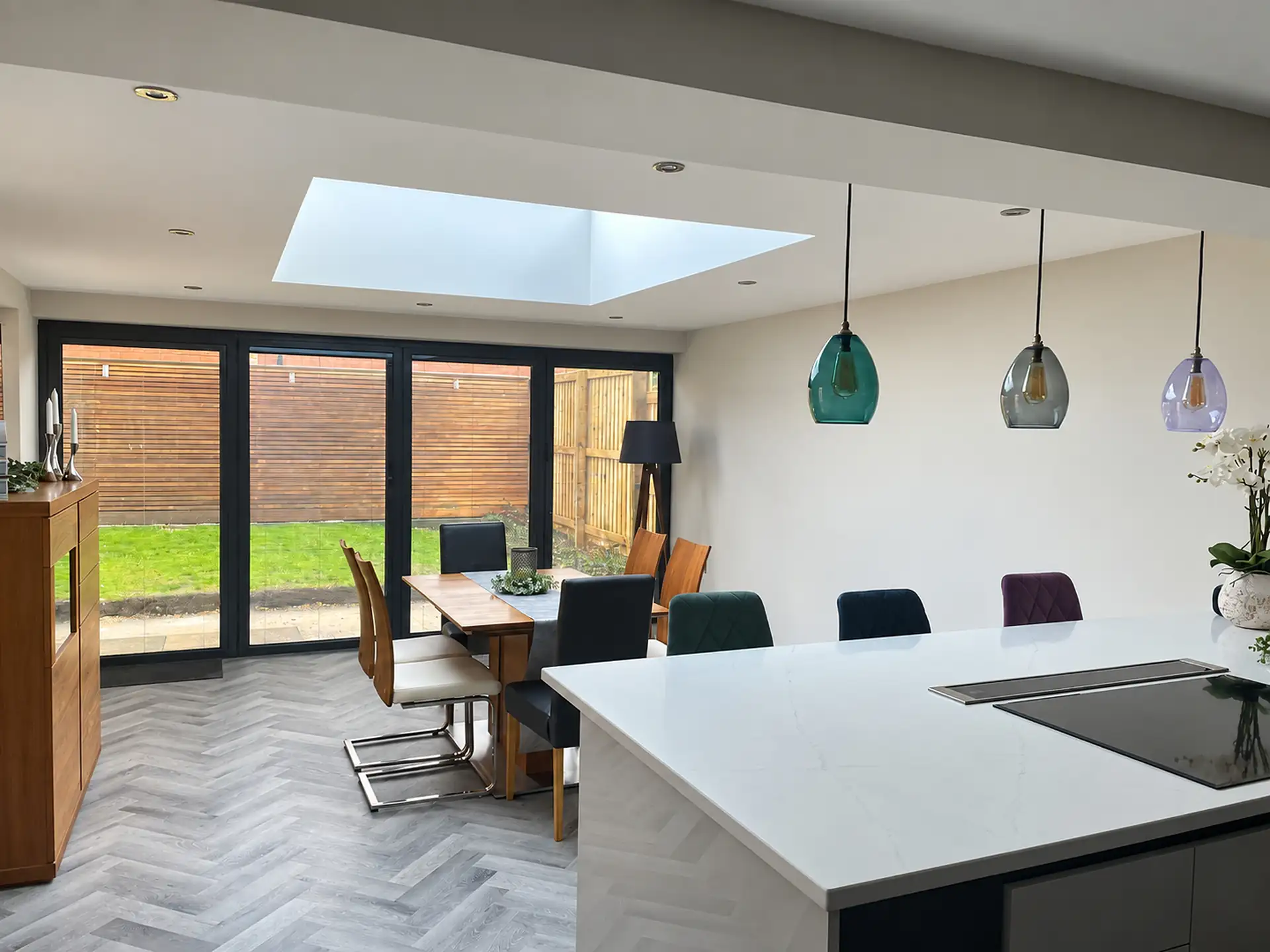 Open plan kitchen with island and dining table under a rooflight