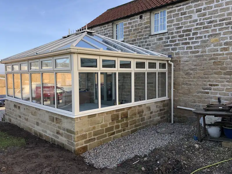 Stone orangery against a farmhouse